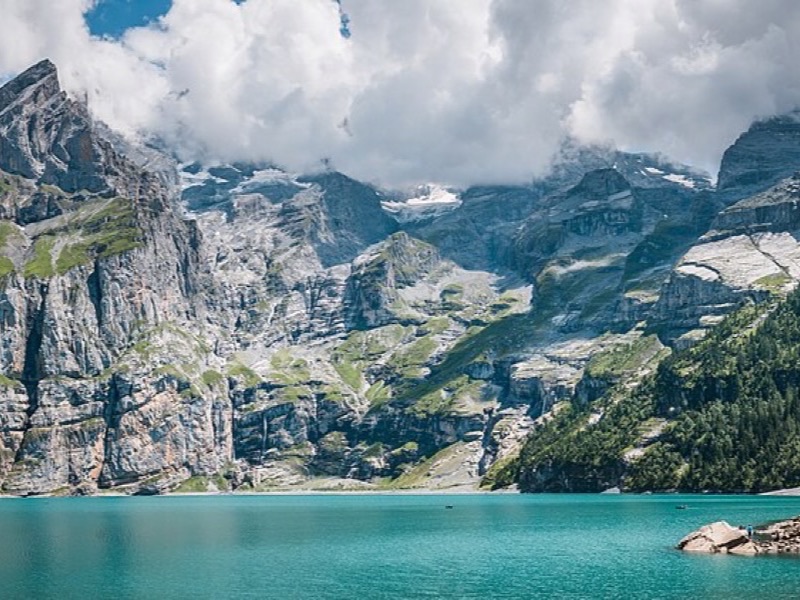 Turquoise alpine lake ringed by forested slopes